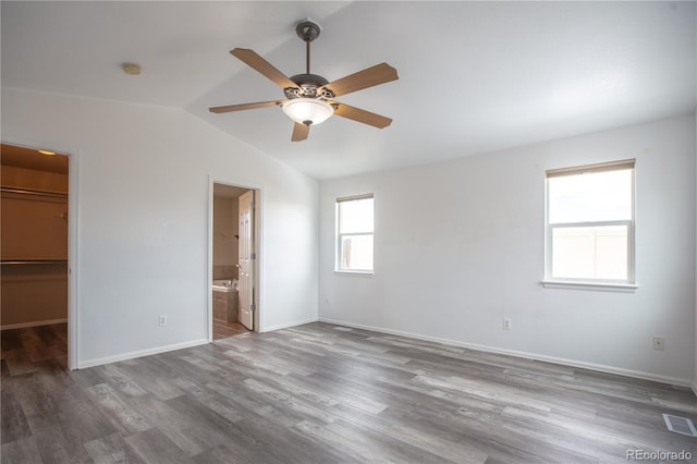 unfurnished bedroom featuring ceiling fan, wood-type flooring, a spacious closet, vaulted ceiling, and a closet