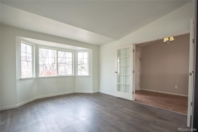 spare room with vaulted ceiling, dark wood-type flooring, a wealth of natural light, and a chandelier