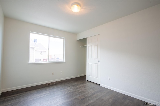 unfurnished bedroom featuring dark hardwood / wood-style floors and a closet