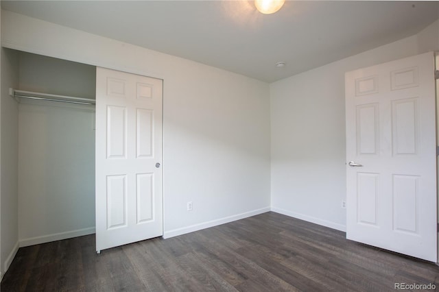 unfurnished bedroom with dark hardwood / wood-style flooring and a closet