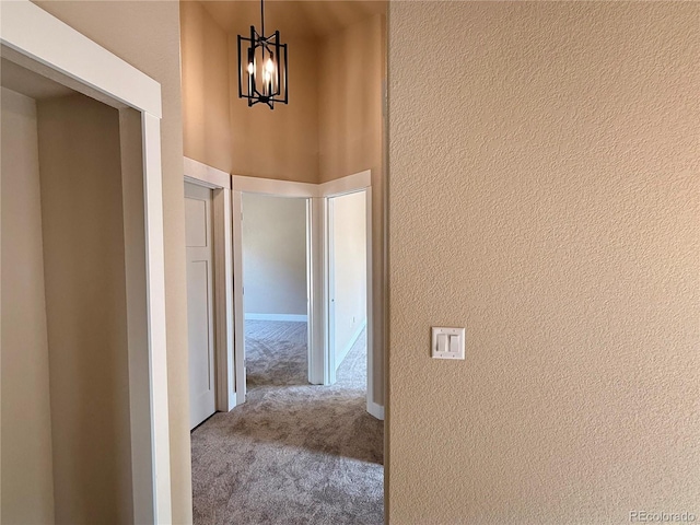 826 Meadow Ln, Palmer Lake, CO 80133 - hall with carpet floors, a textured wall, and a chandelier