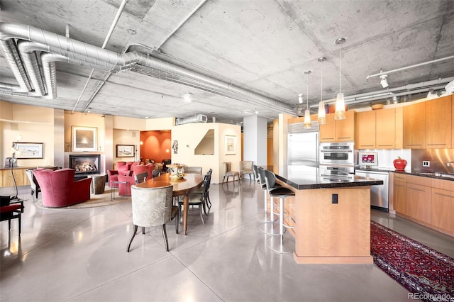 kitchen featuring a breakfast bar area, decorative light fixtures, light brown cabinets, appliances with stainless steel finishes, and a kitchen island