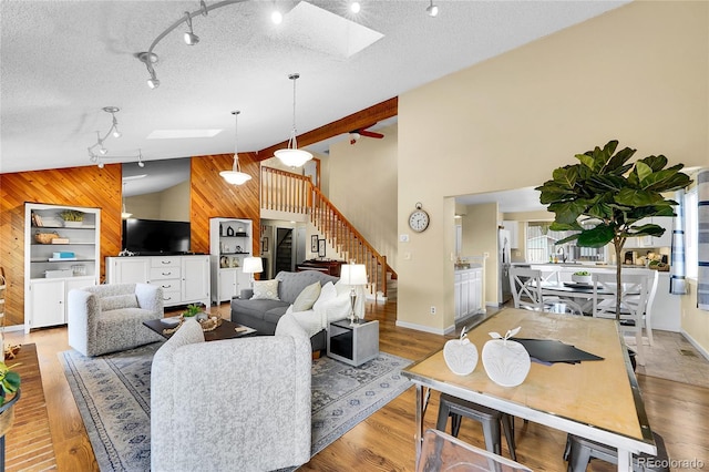 11149 Seton Pl, Westminster, CO 80031 - living room featuring wooden walls, a skylight, rail lighting, stairway, and light wood finished floors