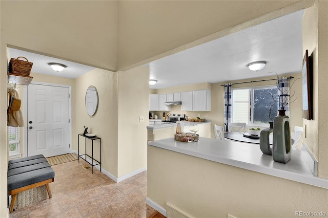11149 Seton Pl, Westminster, CO 80031 - kitchen with range, white cabinets, a peninsula, light countertops, and light stone finish flooring