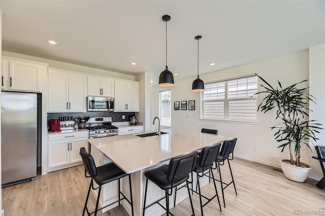 8982 Spaulding St, Parker, CO 80134 - kitchen with stainless steel appliances, a sink, light wood finished floors, a kitchen bar, and tasteful backsplash