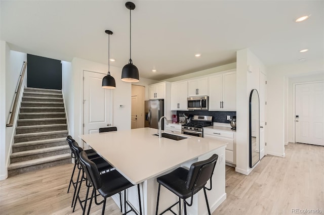 8982 Spaulding St, Parker, CO 80134 - kitchen with appliances with stainless steel finishes, a sink, light wood finished floors, a kitchen bar, and recessed lighting