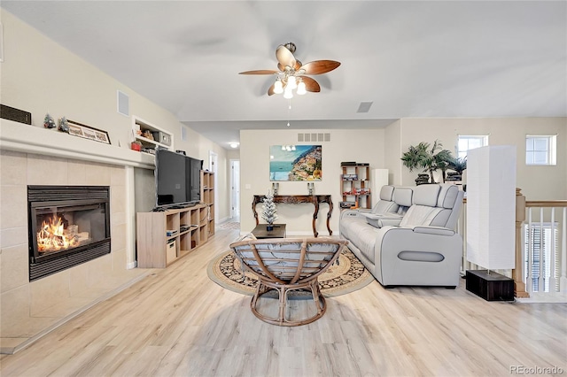 living room with ceiling fan, a fireplace, and light hardwood / wood-style flooring