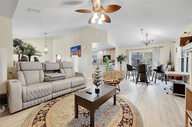 living room featuring ceiling fan with notable chandelier, light wood-type flooring, and vaulted ceiling