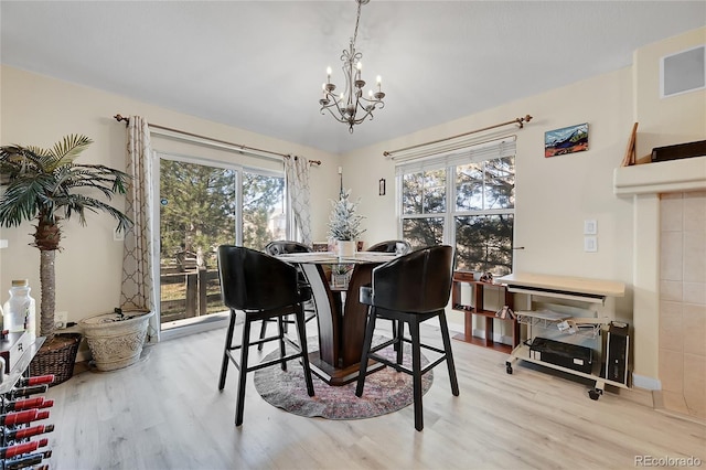 dining area featuring a healthy amount of sunlight, light hardwood / wood-style floors, and an inviting chandelier