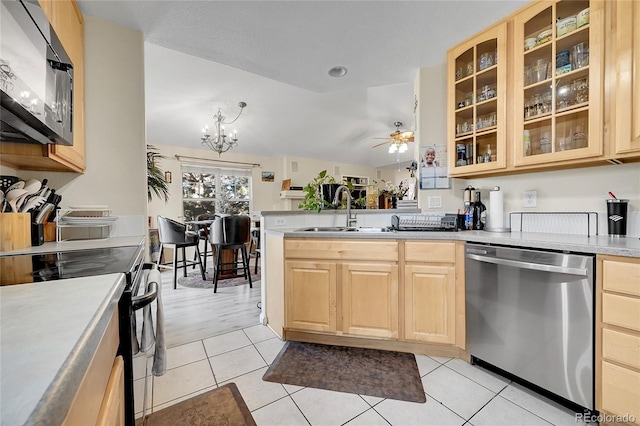 kitchen featuring ceiling fan with notable chandelier, sink, vaulted ceiling, light wood-type flooring, and stainless steel appliances