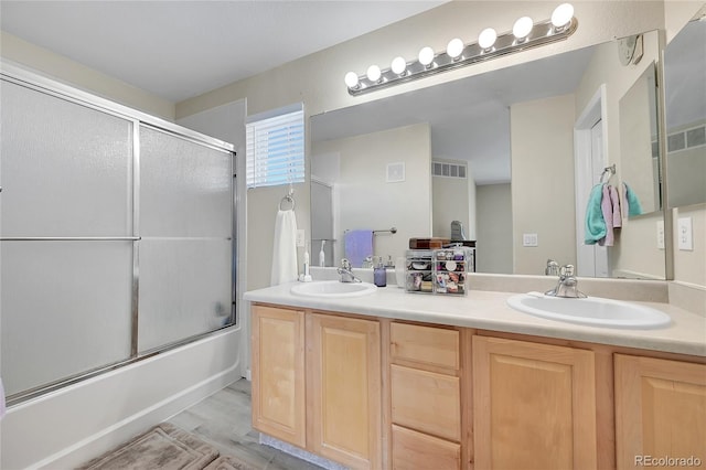 bathroom featuring wood-type flooring, vanity, and enclosed tub / shower combo