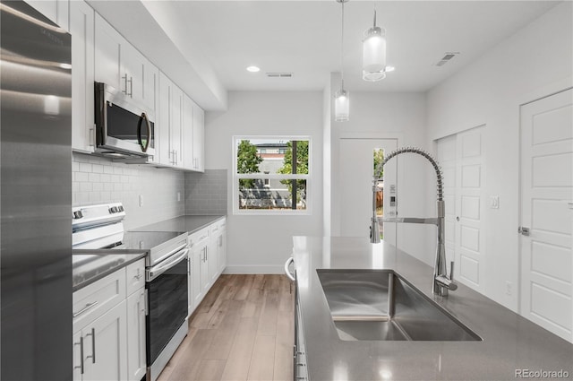 kitchen featuring sink, stainless steel appliances, light hardwood / wood-style floors, decorative light fixtures, and white cabinets