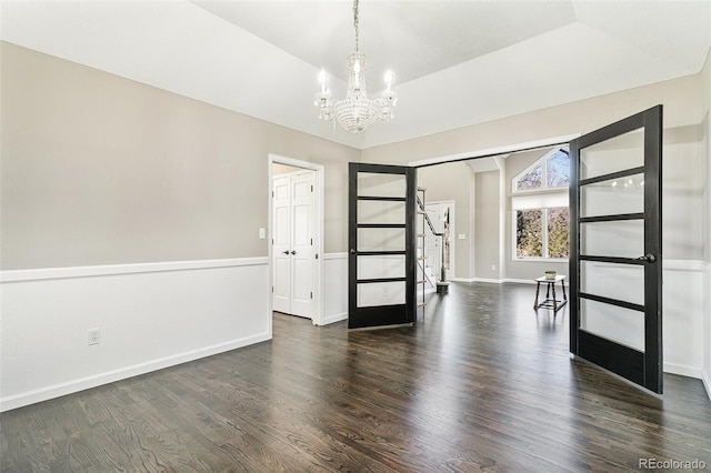 spare room with baseboards, a notable chandelier, wood finished floors, and vaulted ceiling