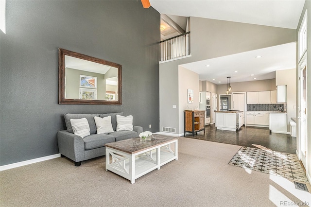 living room featuring recessed lighting, baseboards, visible vents, and high vaulted ceiling