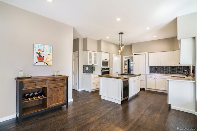 kitchen featuring a center island, wine cooler, decorative backsplash, stainless steel appliances, and a sink