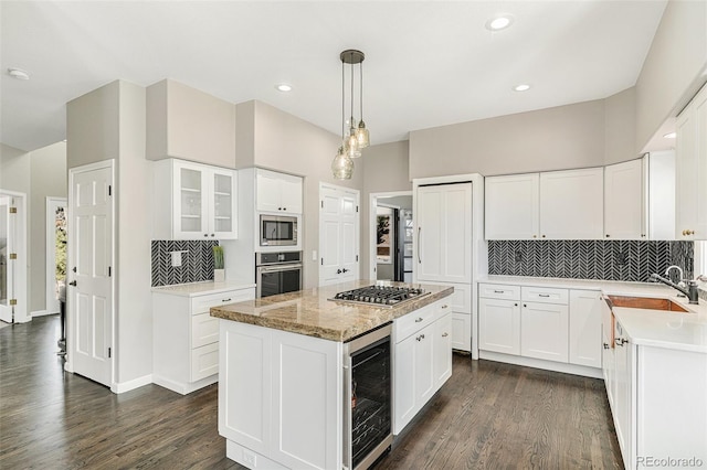 kitchen featuring beverage cooler, a sink, a kitchen island, appliances with stainless steel finishes, and dark wood-style flooring