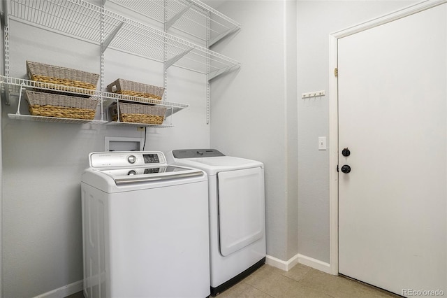 laundry room featuring light tile patterned floors, baseboards, laundry area, and washing machine and clothes dryer