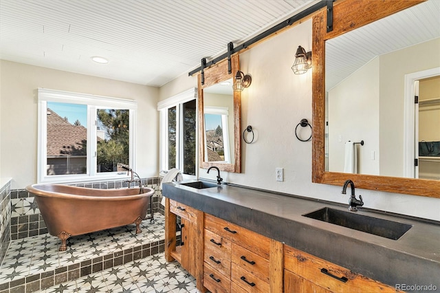 full bathroom featuring a freestanding bath, double vanity, tile patterned floors, and a sink