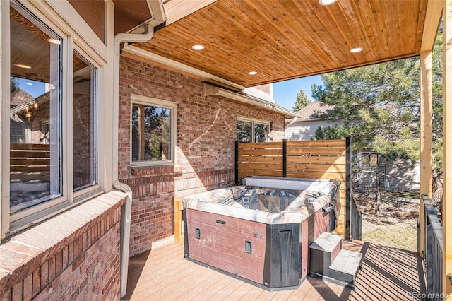 view of patio with a hot tub, a deck, and fence