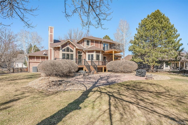 rear view of property with fence, a lawn, a chimney, a balcony, and a patio area