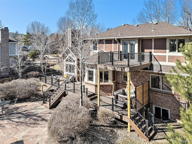 back of property with a patio, stairway, brick siding, and a shingled roof