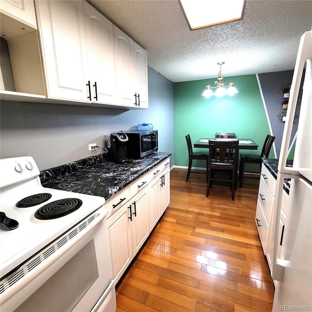 kitchen with white cabinetry, a notable chandelier, light hardwood / wood-style floors, a textured ceiling, and white appliances