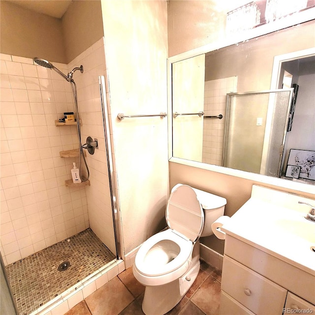 bathroom featuring tile patterned flooring, vanity, toilet, and a shower with shower door