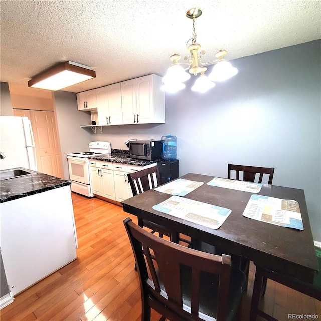 dining room with sink, light hardwood / wood-style floors, a textured ceiling, and a notable chandelier