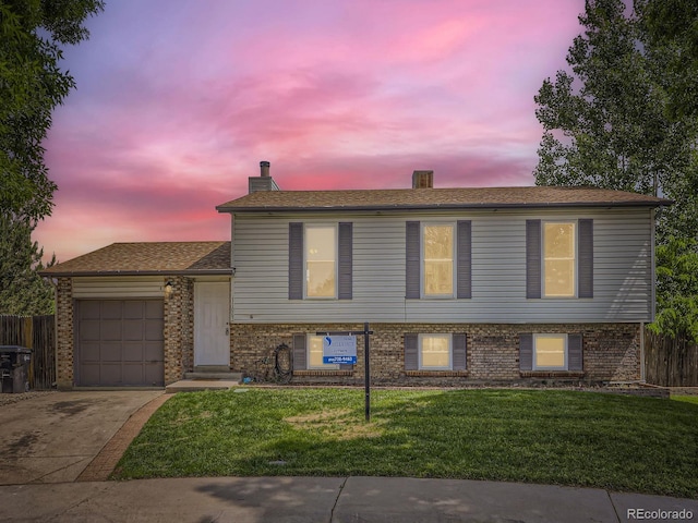 11062 Hudson Ct, Thornton, CO 80233 - split level home featuring a garage, concrete driveway, brick siding, and a chimney
