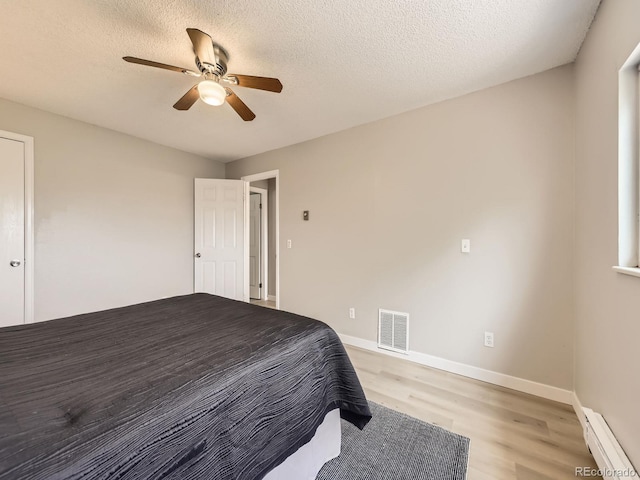 11062 Hudson Ct, Thornton, CO 80233 - bedroom featuring baseboard heating, light wood-type flooring, a ceiling fan, baseboards, and a textured ceiling