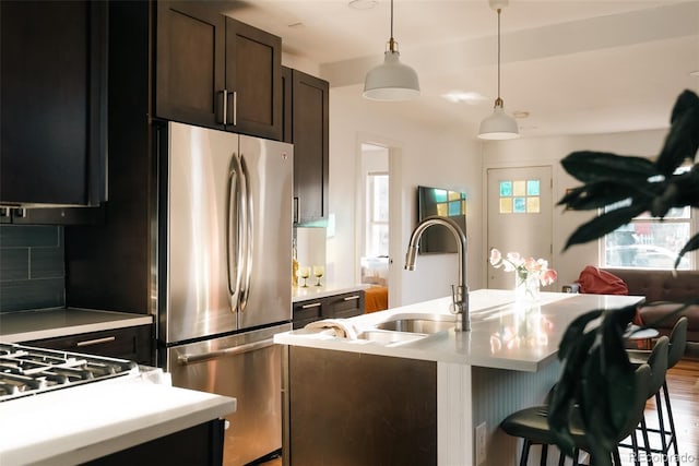 kitchen with open floor plan, freestanding refrigerator, pendant lighting, light countertops, and a breakfast bar