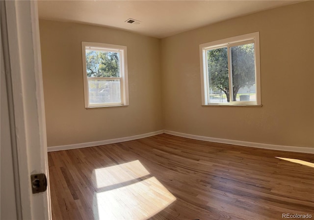 spare room featuring plenty of natural light and hardwood / wood-style floors