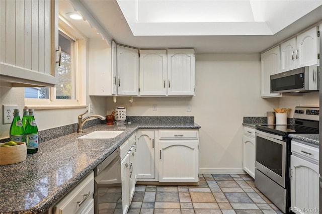 3053 Mcintosh Dr, Longmont, CO 80503 - kitchen featuring appliances with stainless steel finishes, stone finish floors, white cabinetry, and dark stone countertops