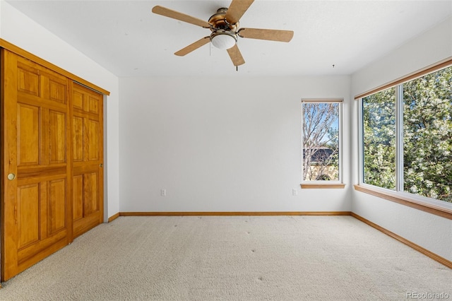 unfurnished bedroom with light carpet, baseboards, and a ceiling fan