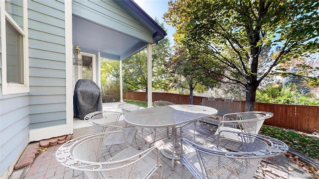 view of patio with outdoor dining space, area for grilling, and fence