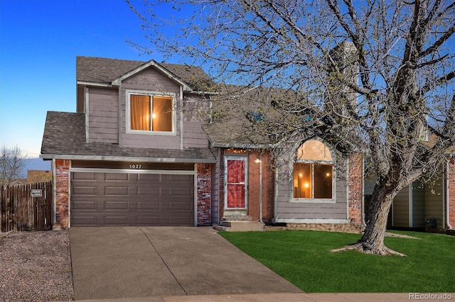 traditional-style house featuring a garage, fence, a front yard, brick siding, and driveway