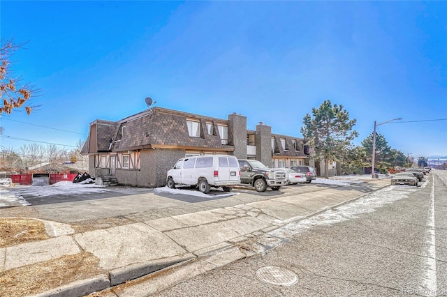 view of front facade with uncovered parking, a residential view, mansard roof, and roof with shingles