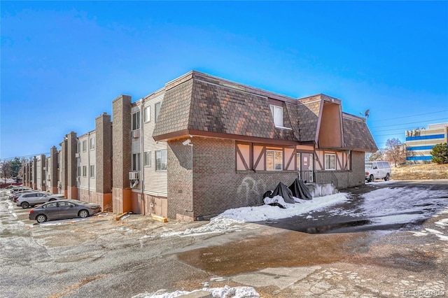 exterior space featuring a residential view, mansard roof, cooling unit, and brick siding