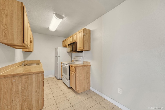 kitchen featuring light tile patterned floors, white appliances, a sink, baseboards, and light countertops