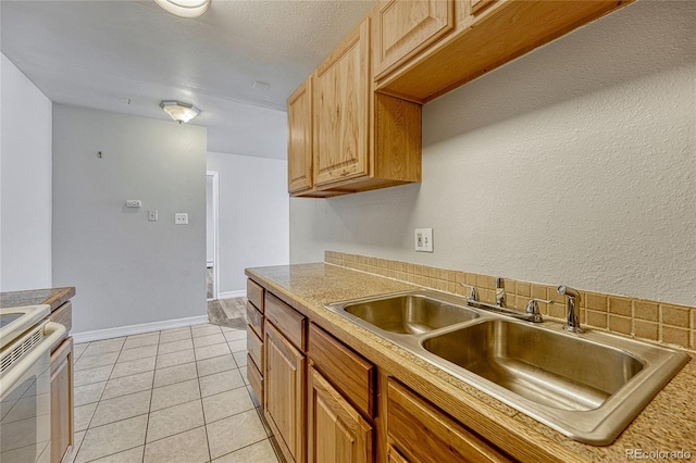 kitchen featuring white range with electric stovetop, light countertops, light tile patterned flooring, a sink, and baseboards