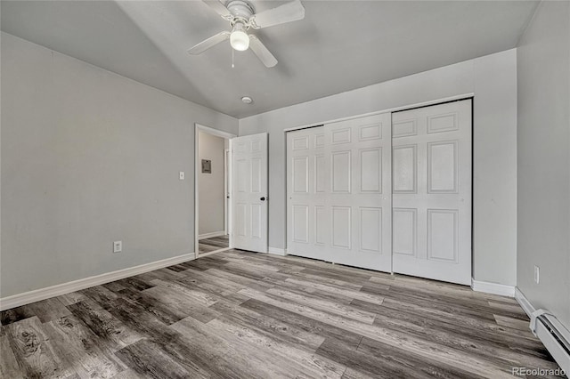 unfurnished bedroom with a ceiling fan, baseboards, baseboard heating, light wood-type flooring, and a closet