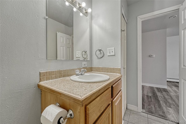 bathroom featuring a baseboard heating unit, vanity, baseboards, and tile patterned floors