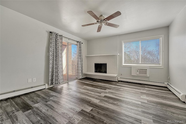 unfurnished living room featuring baseboard heating, a brick fireplace, ceiling fan, wood finished floors, and a wall mounted air conditioner