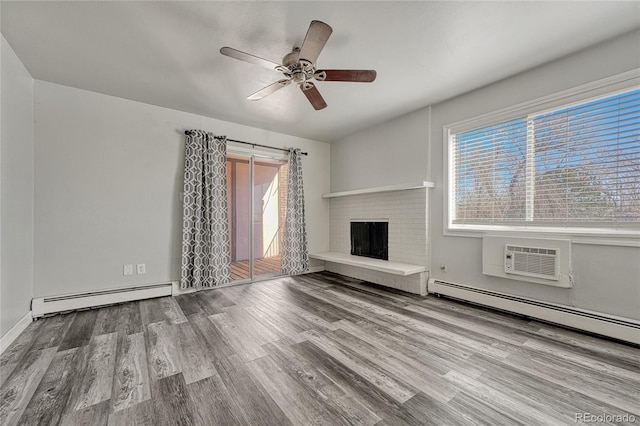 unfurnished living room with an AC wall unit, baseboard heating, a brick fireplace, and wood finished floors