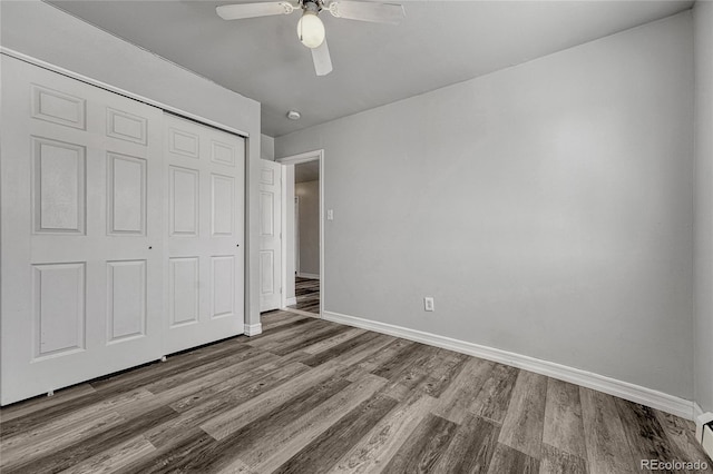 unfurnished bedroom with a closet, ceiling fan, baseboards, and wood finished floors