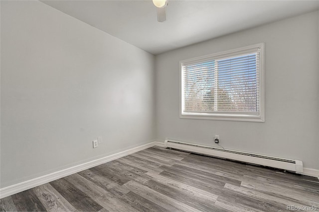 spare room featuring a baseboard heating unit, ceiling fan, light wood-type flooring, and baseboards