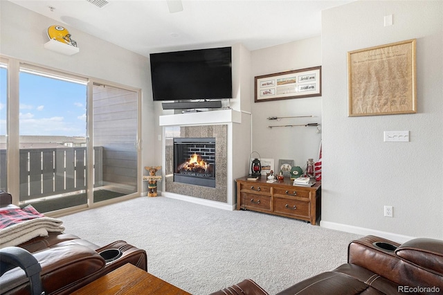 carpeted living area with a warm lit fireplace, visible vents, and baseboards