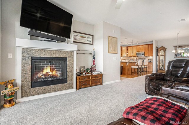 carpeted living room with track lighting, a glass covered fireplace, visible vents, and baseboards