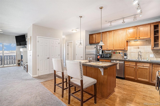 kitchen with appliances with stainless steel finishes, brown cabinetry, a sink, and a kitchen breakfast bar