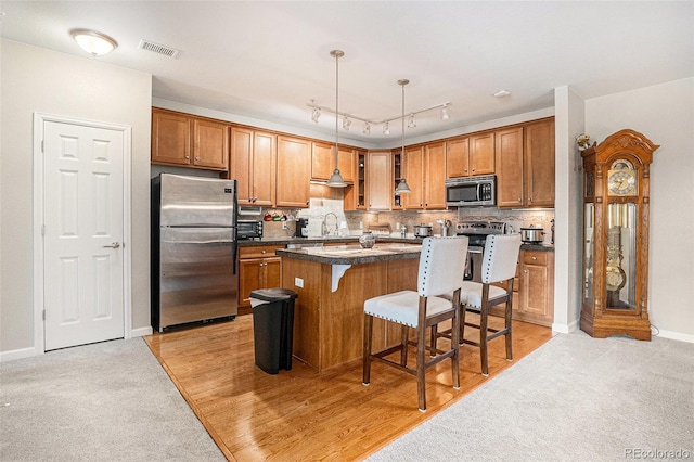 kitchen with tasteful backsplash, dark countertops, stainless steel appliances, a kitchen bar, and a sink